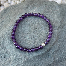 Load image into Gallery viewer, A handmade 6mm amethyst beaded stretch bracelet outside on a stone.

