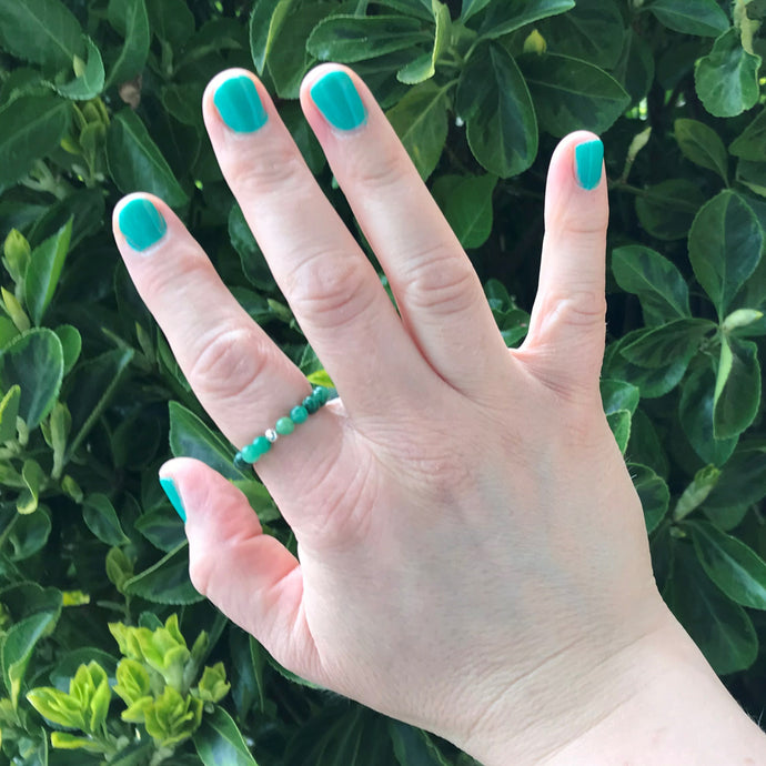 A hand wearing a green gemstone strech ring