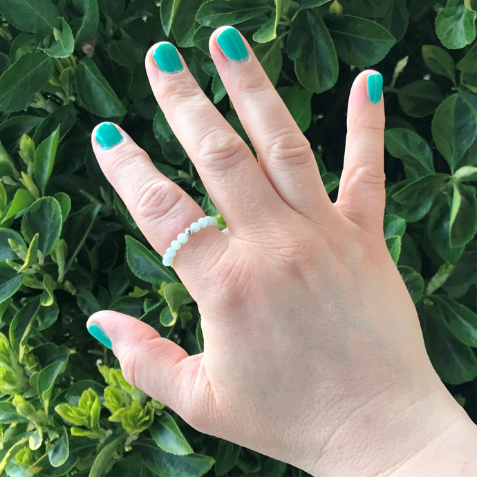 Hand wearing a pale green crystal stretch ring