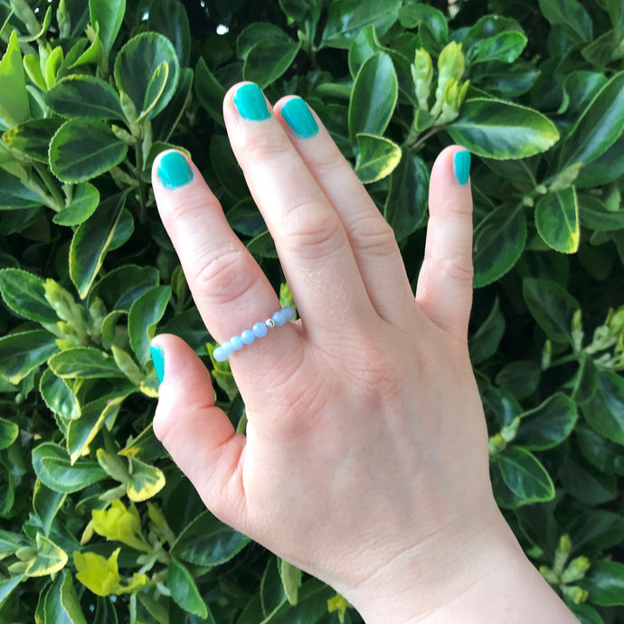 Hand wearing a blue gemstone stretch ring