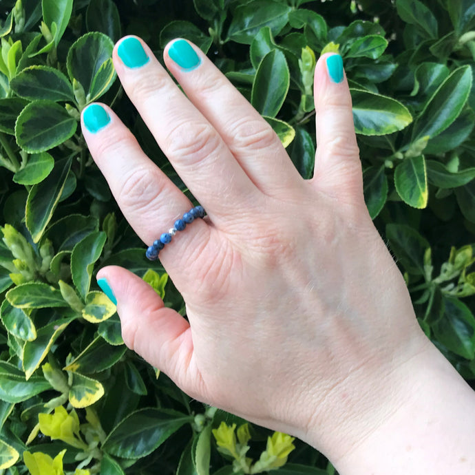 Hand wearing a gemstone beaded dumortierite stretch ring