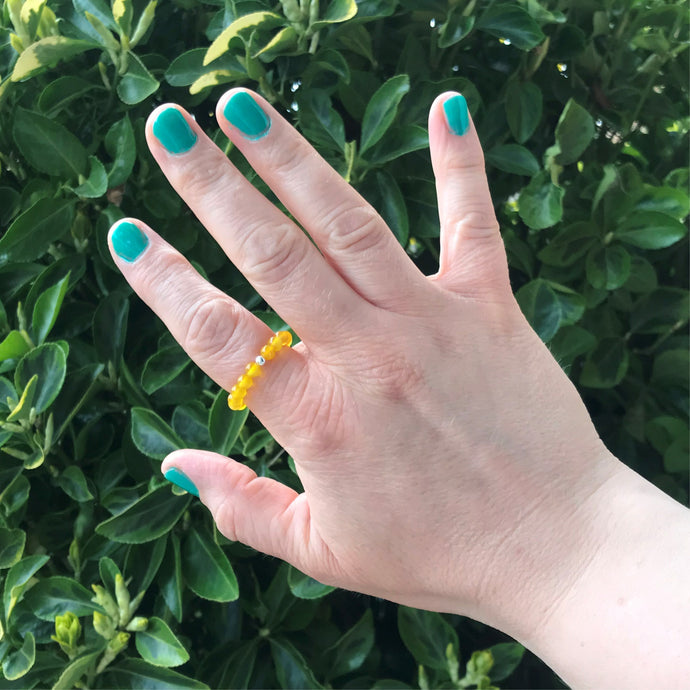 Hand wearing a yellow gemstone stretch ring